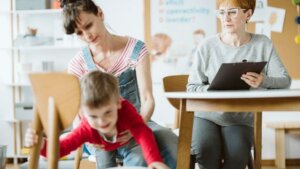 Kid crawling under the table during therapy for ADHD with his mother and professional therapist