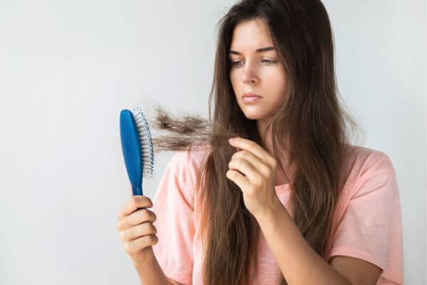 Hair Loss Woman with a Comb in Her Hand on a Light Background